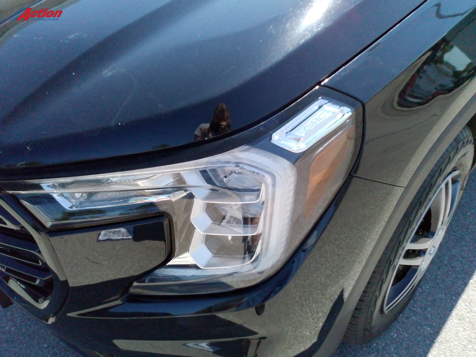 Close-up view of a black vehicle's front headlight and grille.