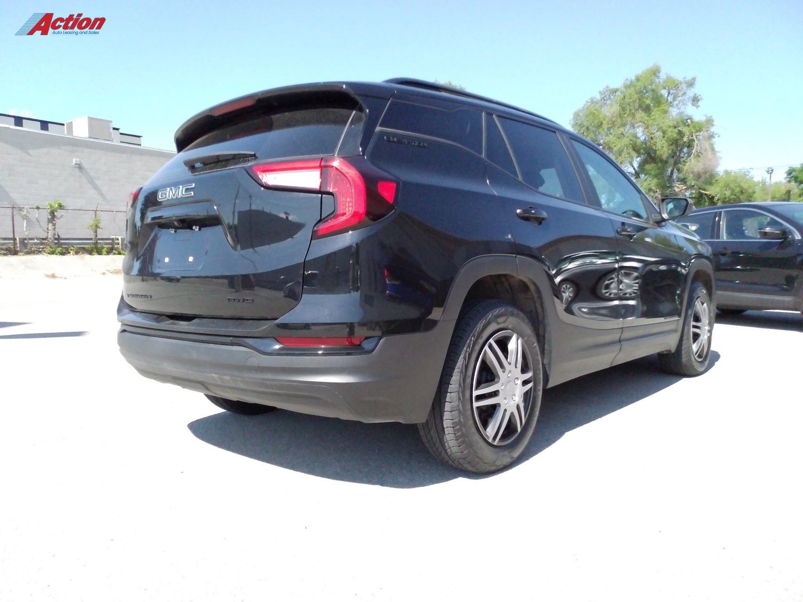 Black GMC SUV parked at a dealership, showcasing its rear and side profile.
