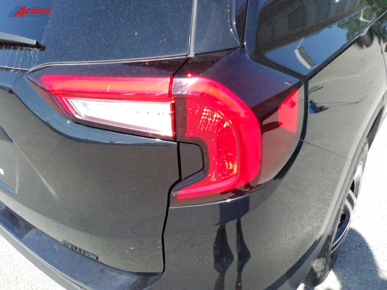 Close-up of the rear taillight of a black vehicle showcasing its design and features.