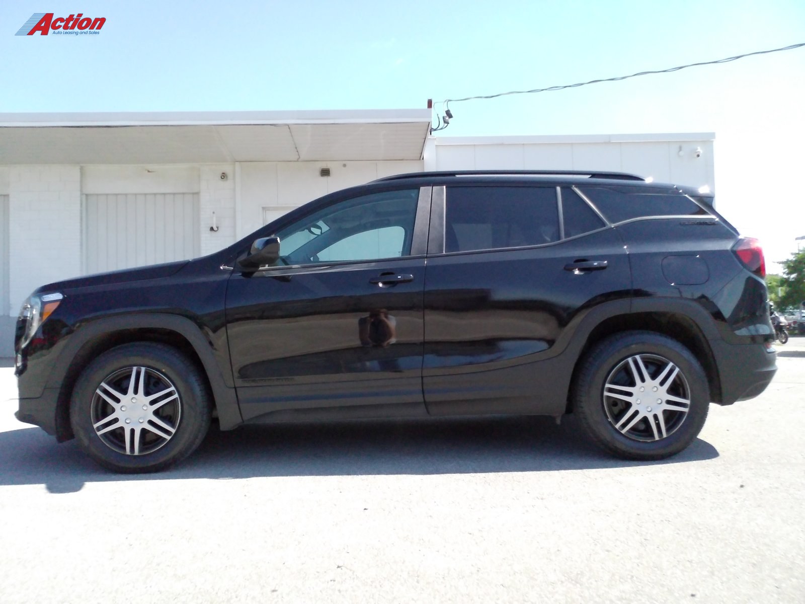 Black SUV parked outside with clear sky and dealership building in the background.