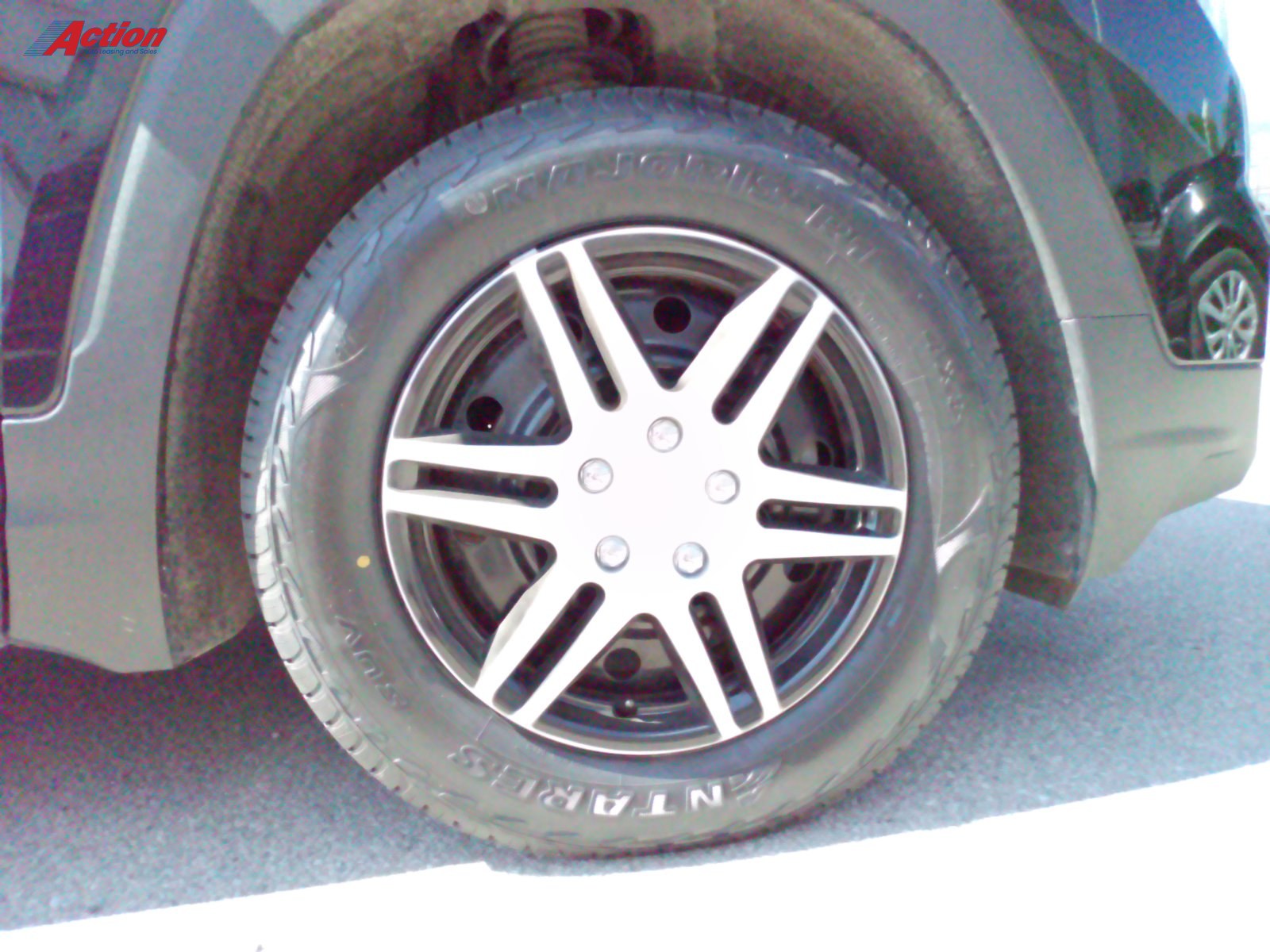 Close-up of a stylish black alloy wheel with a tire on a parked vehicle.