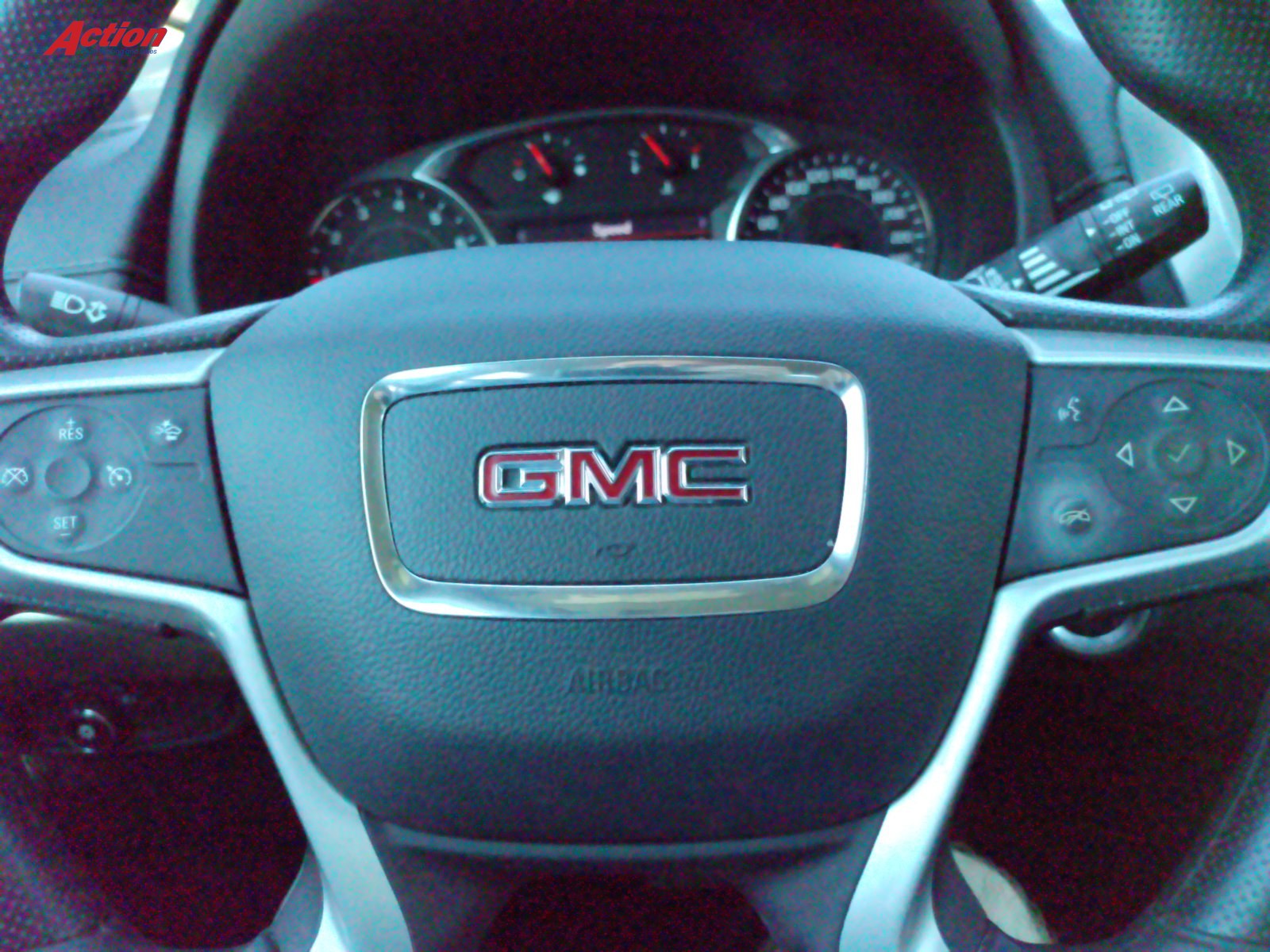 GMC steering wheel with controls and dashboard visible in the background.