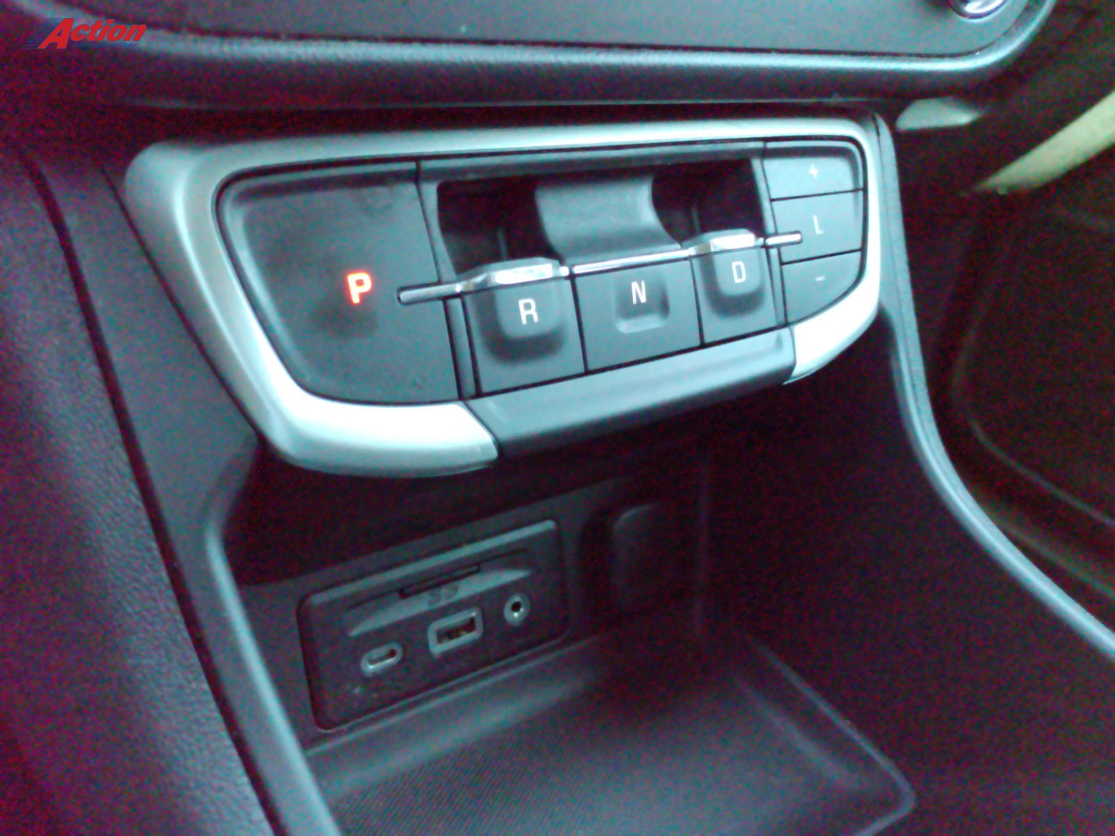 Close-up of the gear shift and control panel in a modern vehicle's interior.
